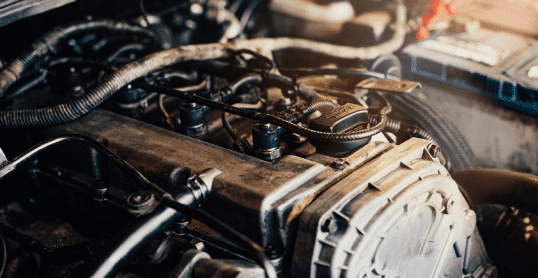 Close-up of a car engine with various components and wiring, highlighting detailed parts and tubing in the sunlight—ideal for those interested in diesel repair or maintaining a diesel truck.